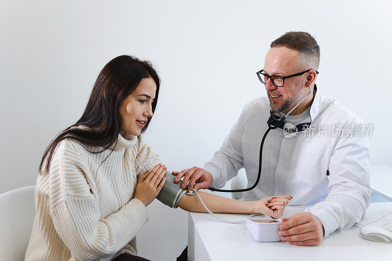 男医生在体检时为一位女病人测量血压。一名心脏病专家