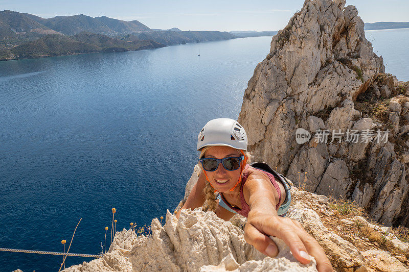 女登山者在海上通过费拉塔到达顶峰的最后一步