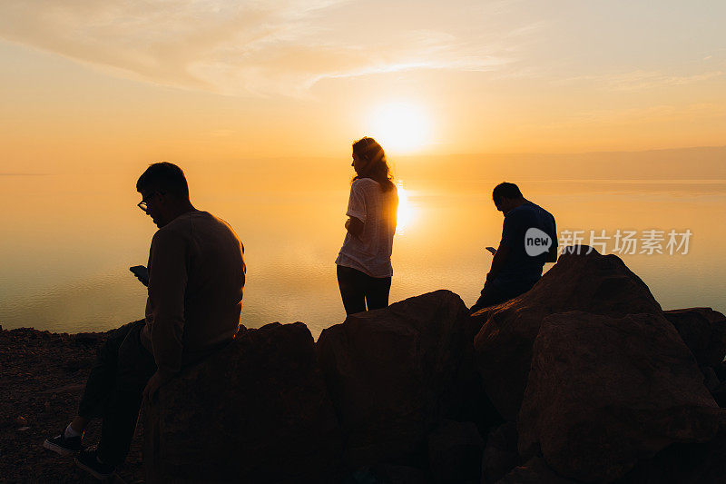 朋友旅行者在约旦的死海上观赏日落美景