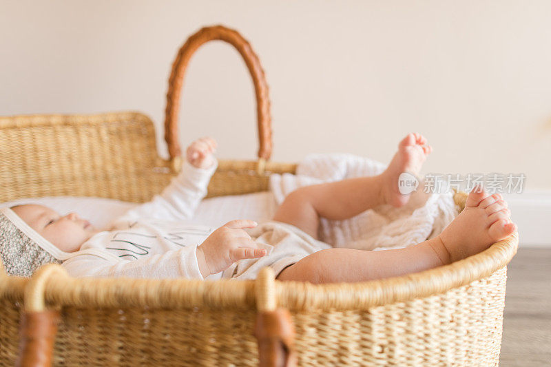 一个14周大的男婴的12个脚趾躺在一个舒适的奶油棉毯子在海草摩西篮子