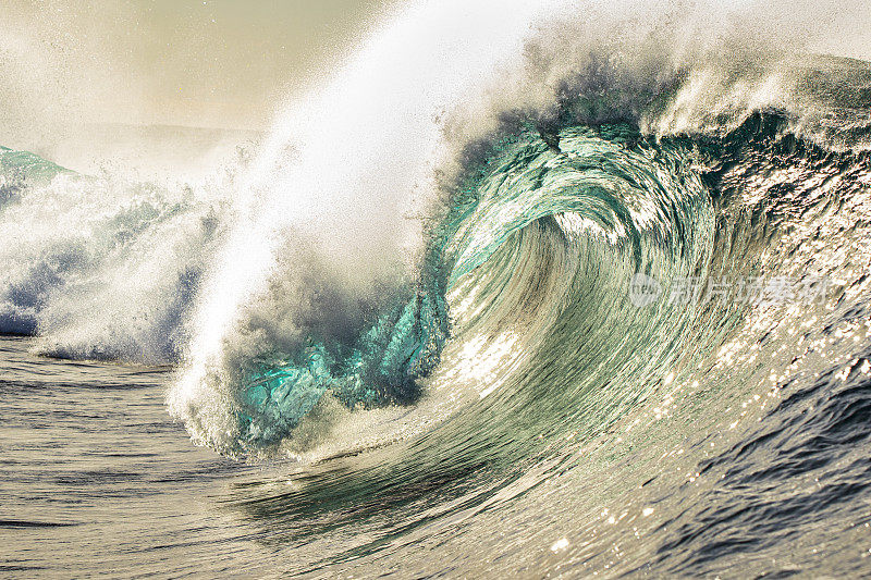 完美的蓝绿色波浪在一个阳光明媚的金色下午打破开放的海洋