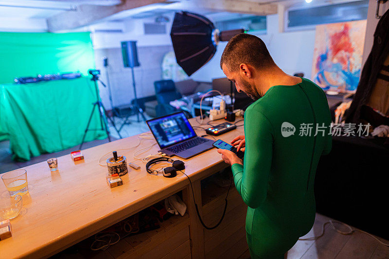 DJ使用手机，在录音棚，同时穿着绿色的西装