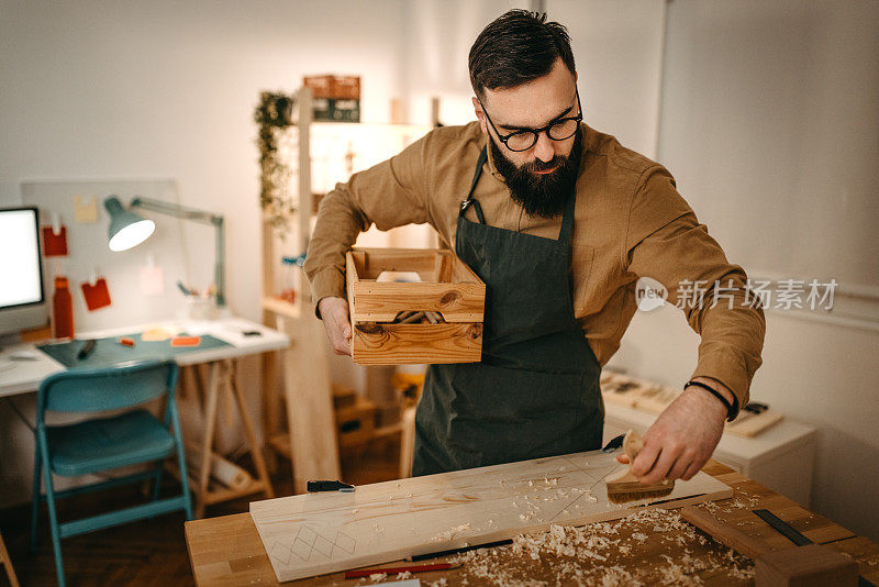 男艺术家在工作室的工作台上用手工工具和木箱