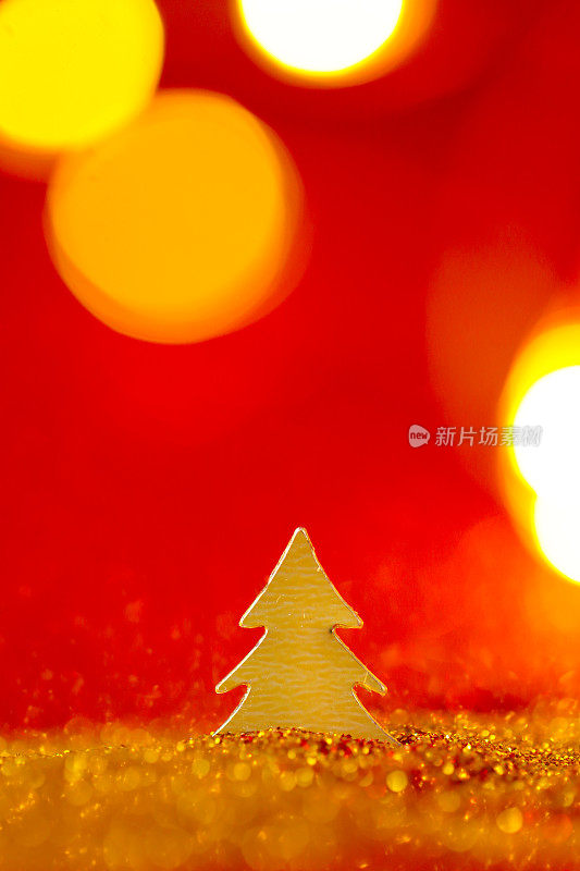 金色和红色的圣诞墙纸。迷你圣诞树在金色闪闪的红色背景上