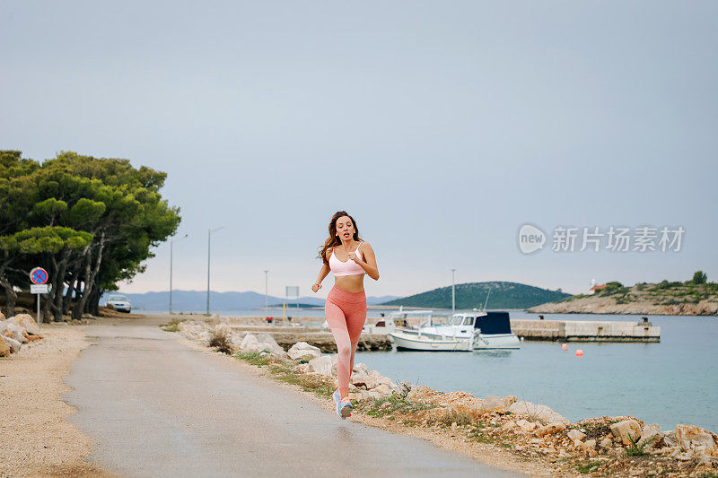 运动女孩正在海滩上跑步