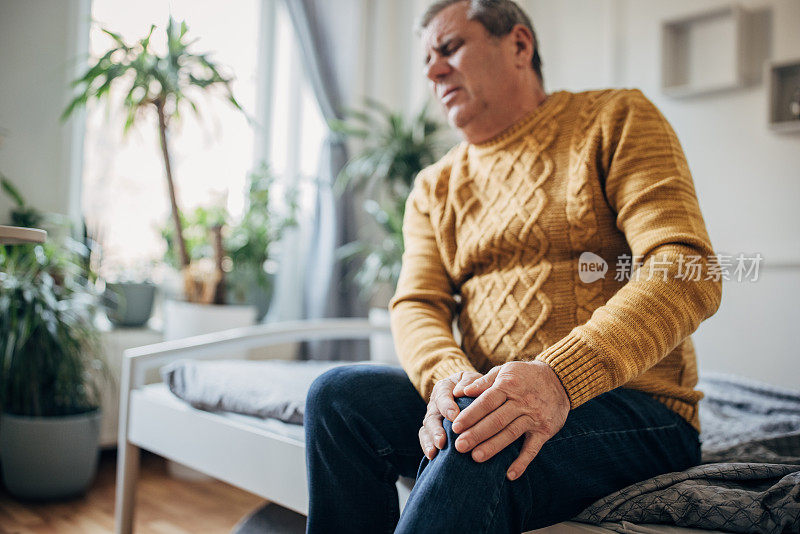 一个男人把手放在生病的膝盖上