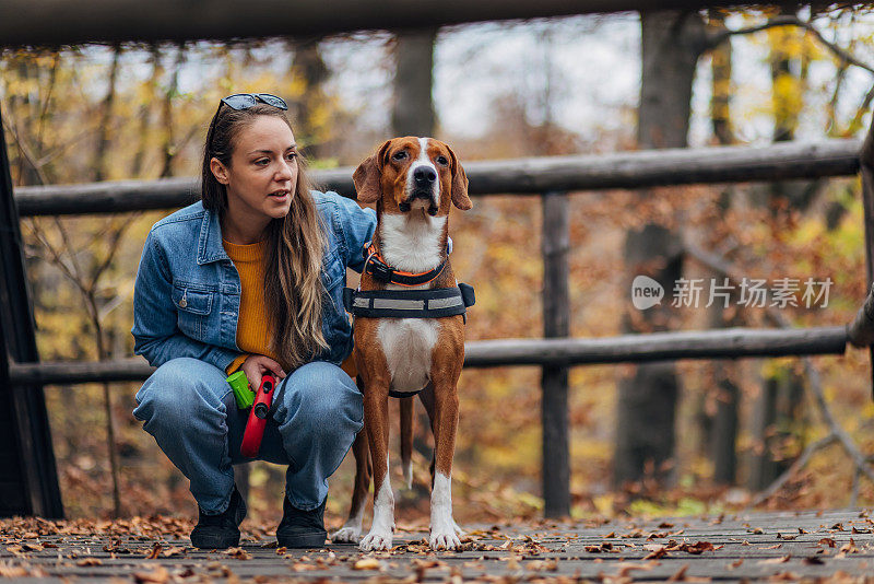 一名妇女抱着她的三色狗，他们站在走廊上散步休息