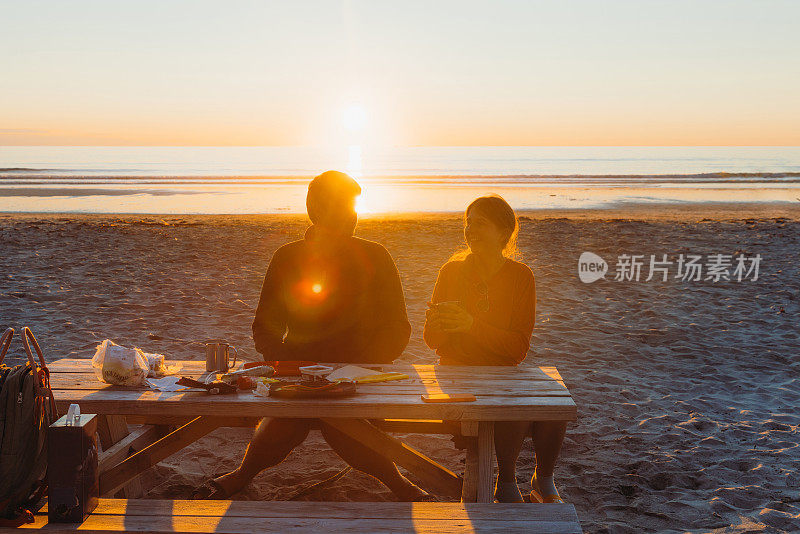 女人和男人在风景优美的海滩露营，在午夜太阳下在罗福特群岛野餐