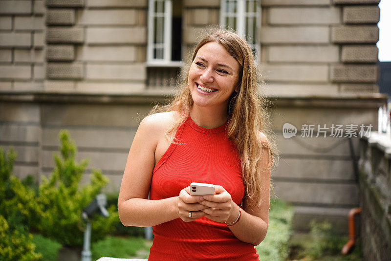 一个美丽的年轻女子在城市里用智能手机发短信的肖像