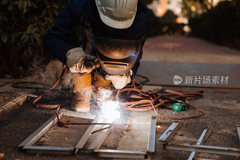 一名中年男性工人正在使用切割机和焊机