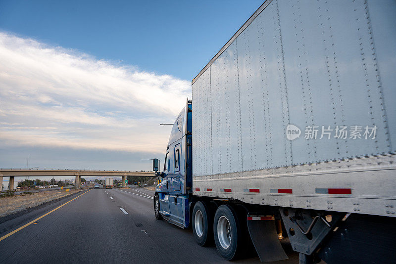 一辆半挂车行驶在双车道公路上，天空中有美丽的云