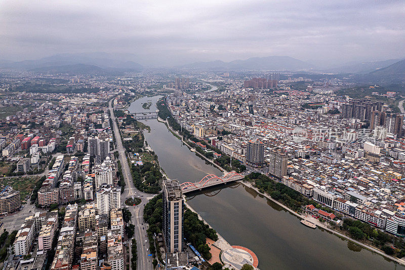 多云天，有河流的城市中人口密集的建筑物鸟瞰图