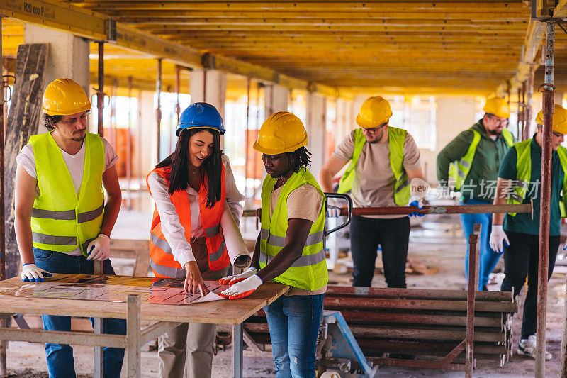 三名建筑工人在施工现场制作建筑平面图