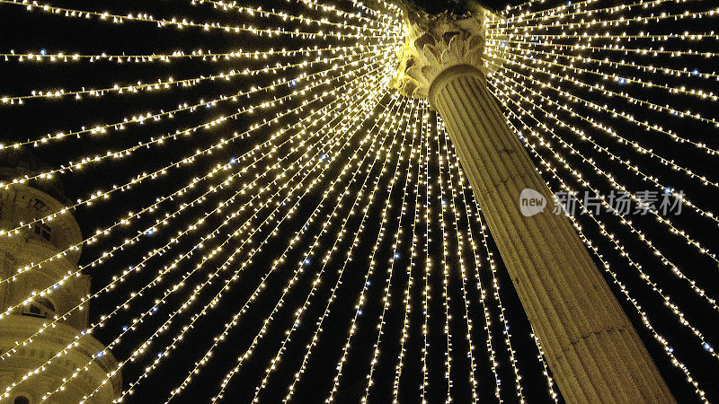 西班牙加利西亚卢戈市圣多明各镇广场上的柱子周围由光点组成的天篷。圣诞装饰品。