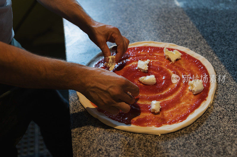 把马苏里拉奶酪放在准备好的披萨面团上