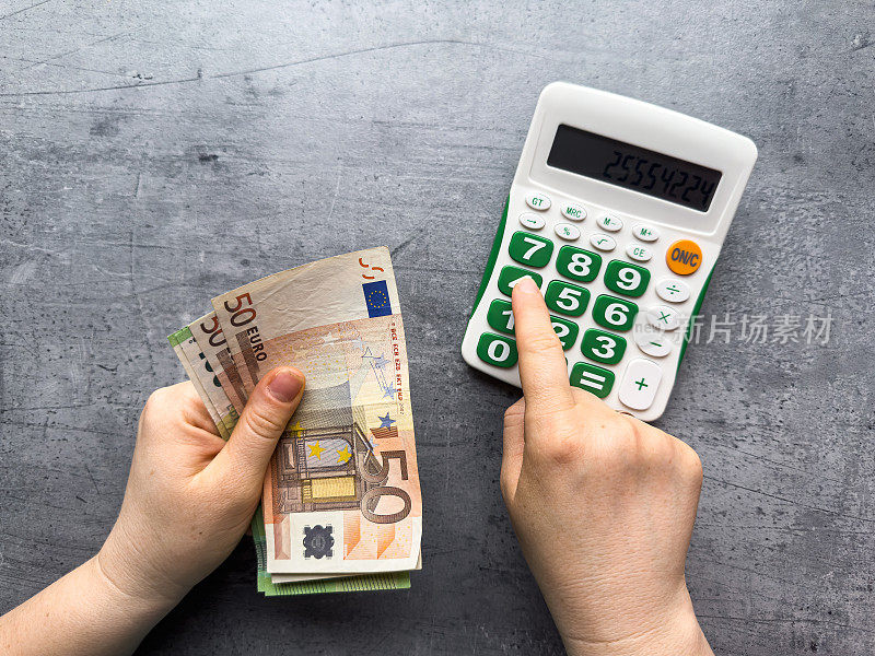 女人用计算器计算欧元钱，如何分摊费用