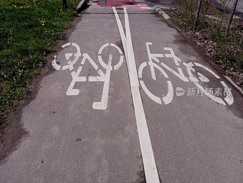 在自行车道上用白色油漆在沥青路面上进行标记。自行车道的沥青路面上画着两辆自行车。道路标记和标志。