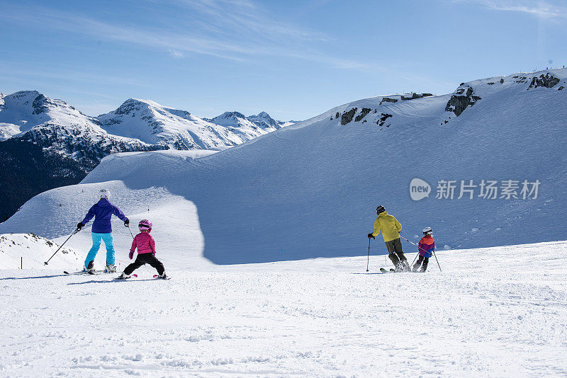 一家人在滑雪场滑下斜坡