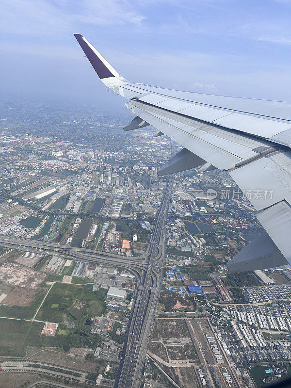 从飞机窗口看到的图像，飞机机翼飞过陆地地形，小翼和板条，高架视图，重点在前景