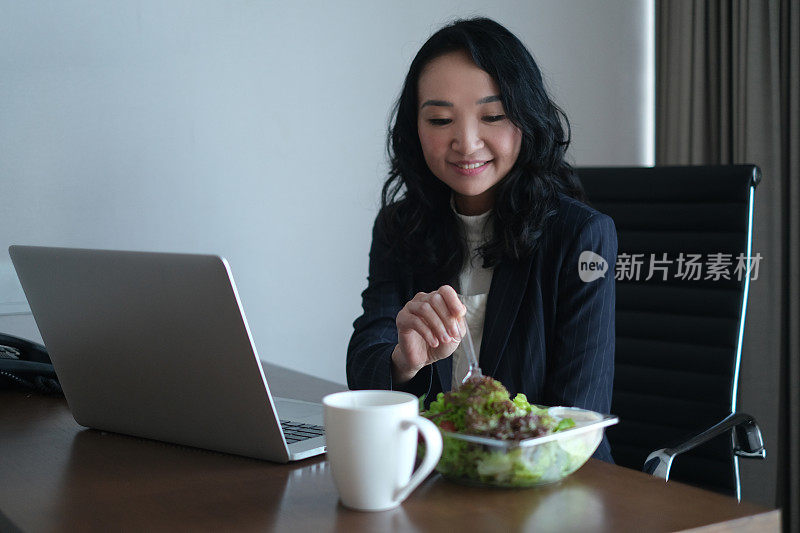 亚洲女商人在办公室吃沙拉