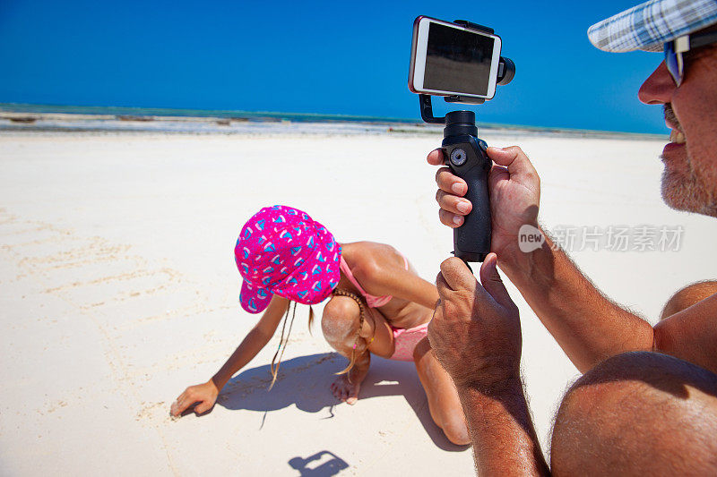 父亲在热带度假的海滩上拍摄女儿