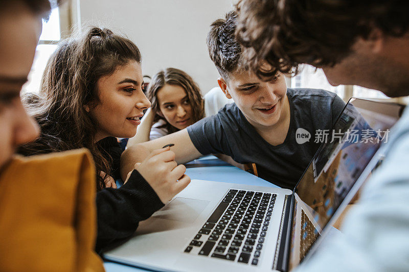 一群青少年在用笔记本电脑聊天和微笑