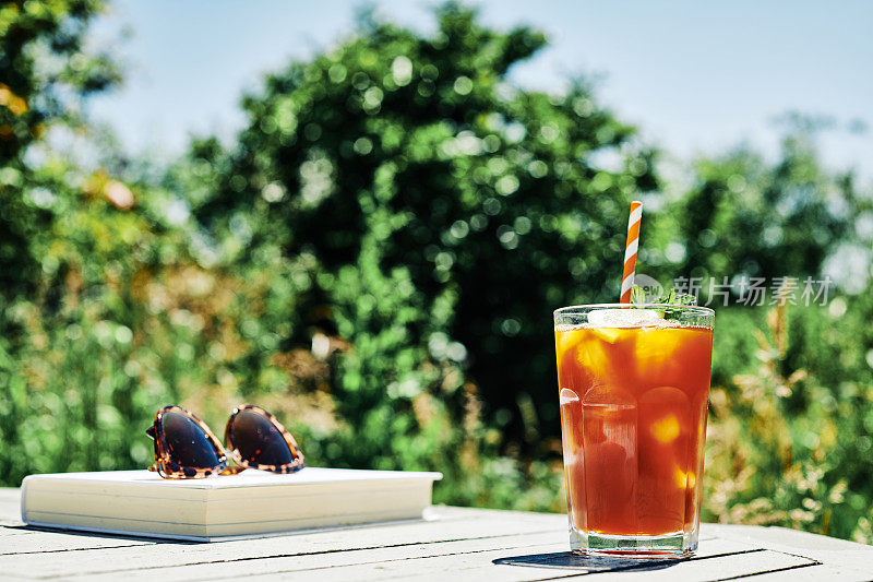 夏日美景，阳光明媚的花园桌上放着柠檬薄荷冰茶。