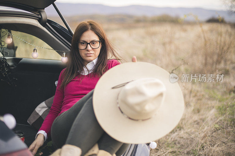 一个年轻女人坐在外面的后备箱里