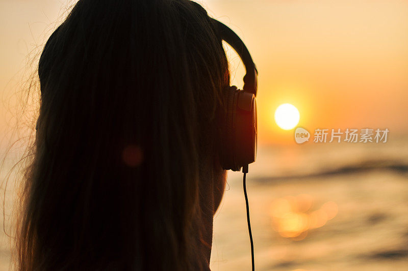 一个女人在日落时听着音乐