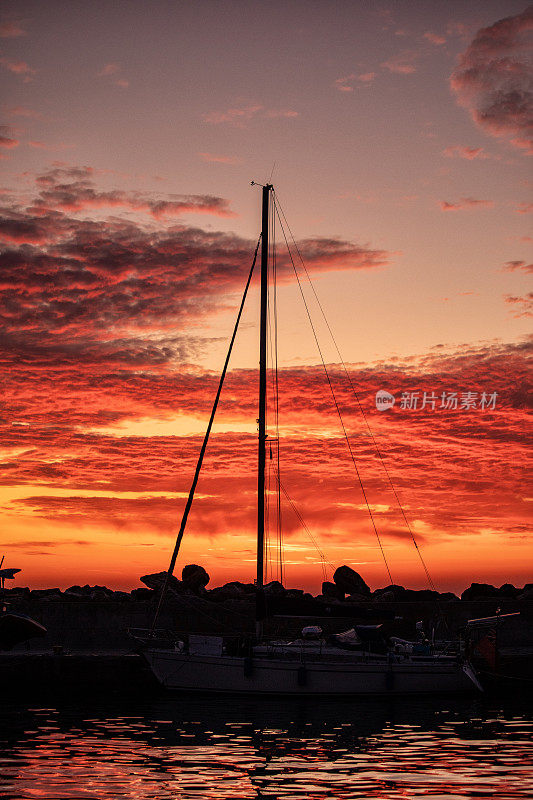 日出时，帆船在壮观的天空映衬下的剪影