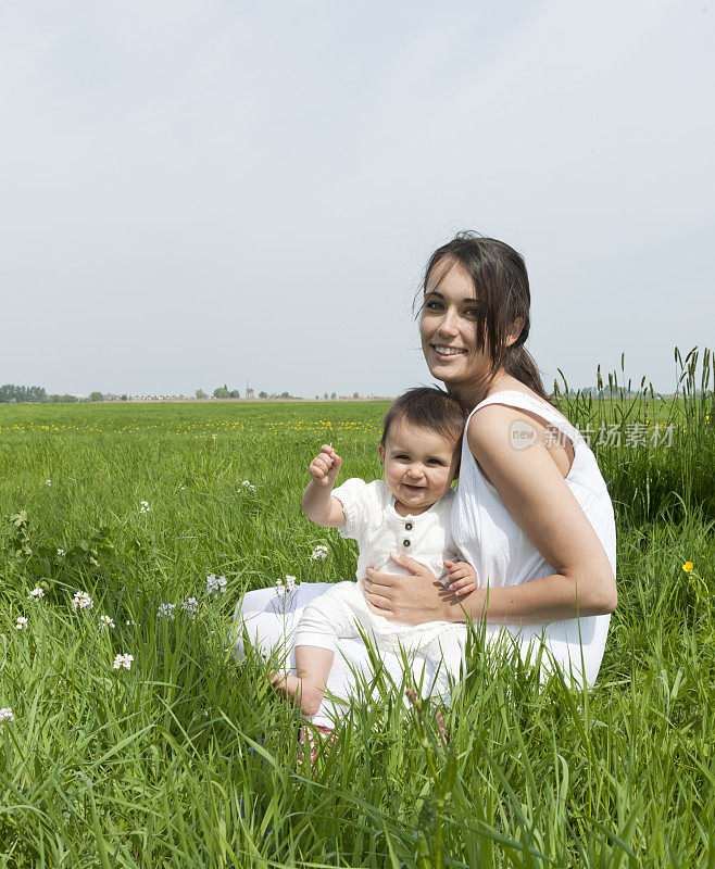 母亲和女婴在春天的草地上
