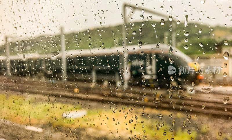 雨点落在一列高速列车的车窗上，在背景中模糊了