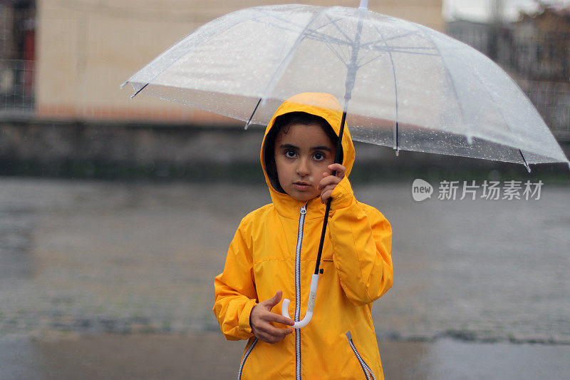 小女孩撑着雨伞在雨中