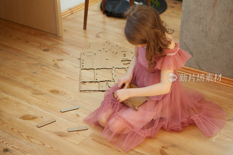 一个女孩玩纸板玩具玩具屋家具。