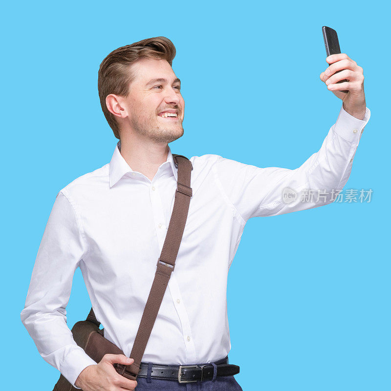 白种人男性摄影站着背着背包和拿着包和使用智能手机