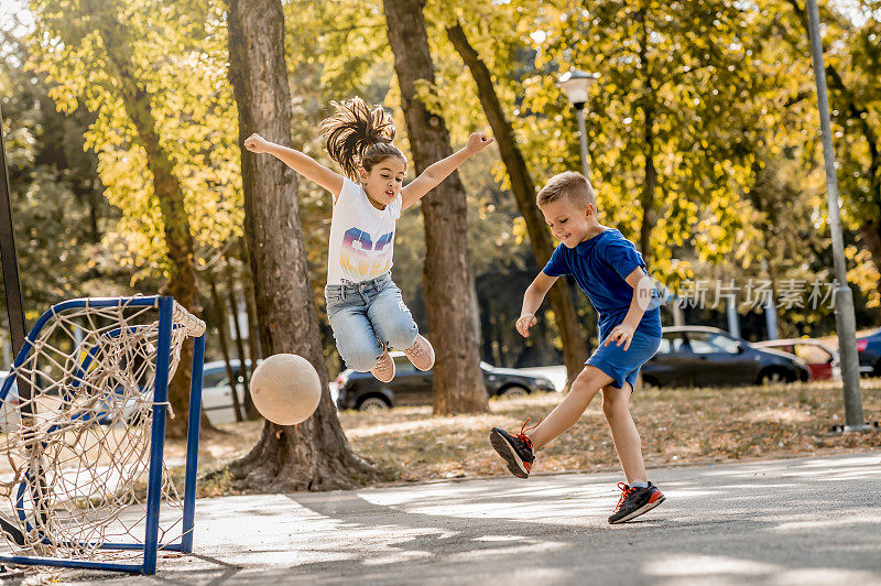 一个小男孩和一个女孩在院子里踢足球。