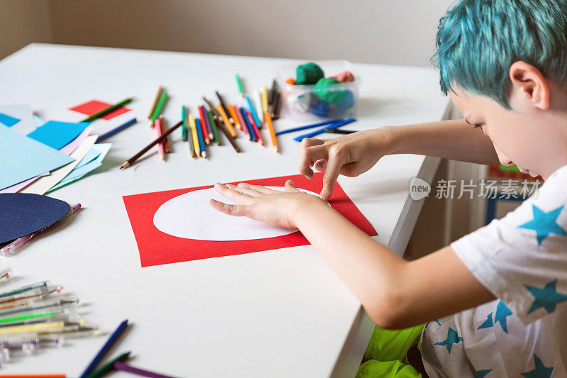 男孩用颜色、纸张和胶水手工制作卡片。孩子们艺术和手工艺。