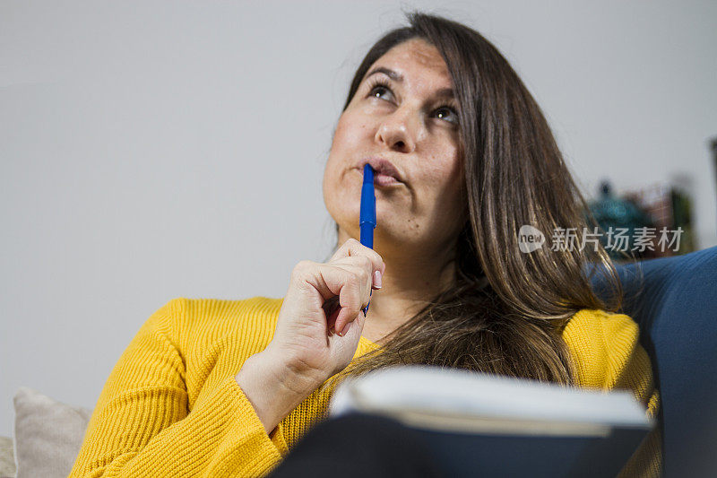 手里拿着笔和笔记本的思考女人