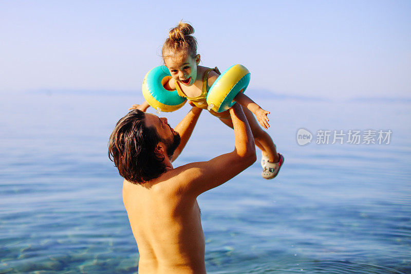 英俊的父亲和他的女儿在海里跳