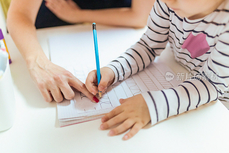 女导师手指着练习册上的笔画动作练习