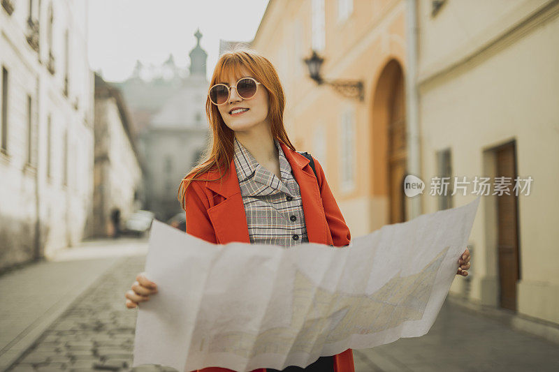 女旅行者在街上看城市地图。旅行，乐趣，度假的概念。