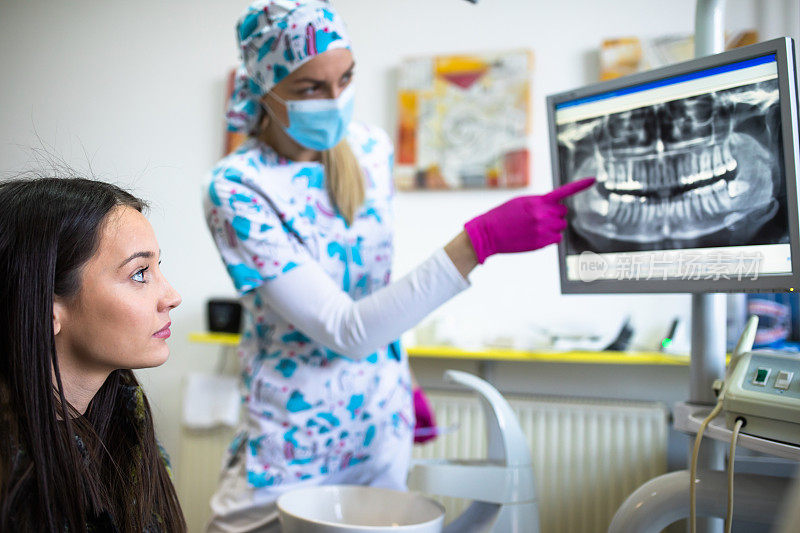 一位年轻的女士和她的牙医在看她的数字牙科x光片