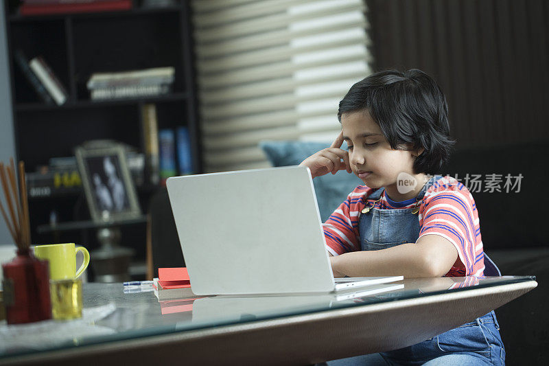 体贴的小女孩在家里做作业和使用笔记本电脑