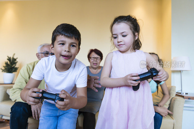 一个男孩和一个小女孩在家里玩电子游戏。的时间和家人在一起。