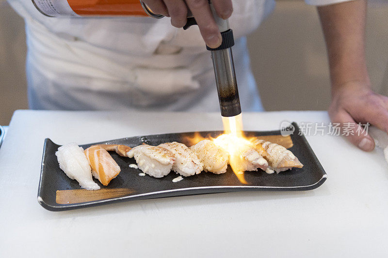 厨师正在用喷枪烤生鱼片寿司