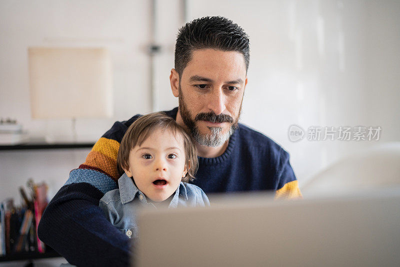 在家里工作的成熟男人带着年幼的儿子——有特殊需要的儿子