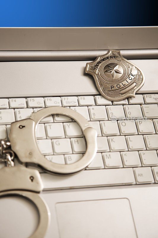 法律的概念。网络安全。带警徽和手铐的笔记本电脑。