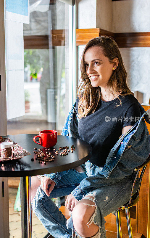 一个年轻的女人坐在咖啡吧里放松