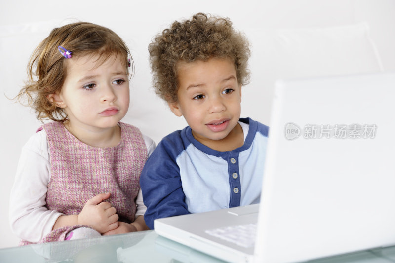 小女孩和小男孩在客厅里使用笔记本电脑