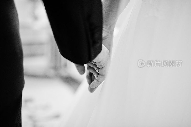 近距离的手牵手的新婚夫妇。黑白照片